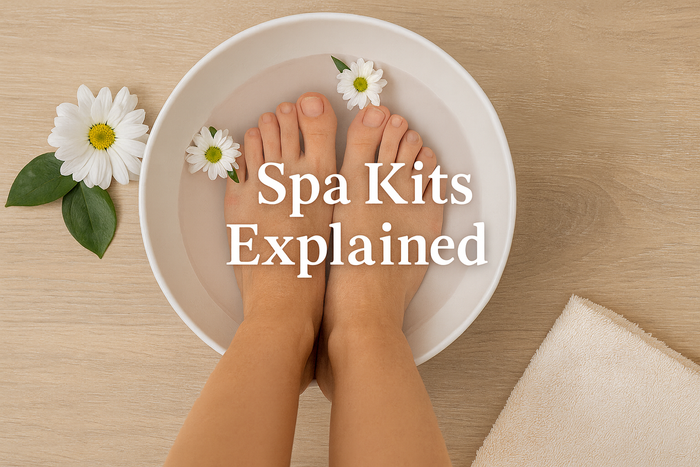 A top-down image of a pair of feet soaking in a white bowl filled with water and floating daisies. The feet are centered in the bowl on a light wood surface, with white daisies and green leaves surrounding the scene. The words 